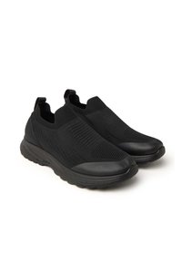 Zapatos negros sin cordones con parte superior de malla, superficie texturizada y suela de goma. Presentan un acolchado suave alrededor del tobillo y una punta redondeada.