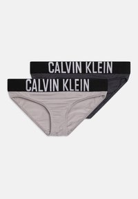 Un paio di slip Calvin Klein in grigio e nero. Presentano un tessuto morbido con una consistenza liscia e una fascia elastica larga con il logo del marchio.