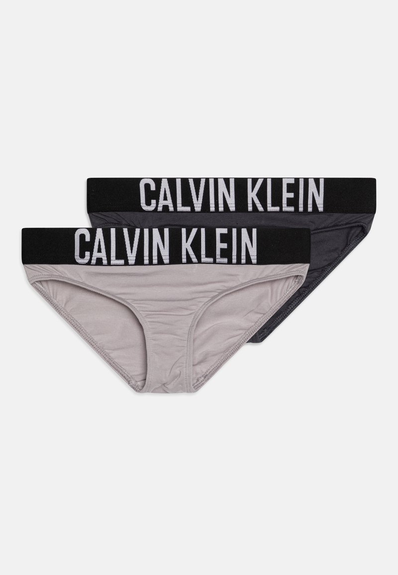 Pár bavlnených slipov Calvin Klein v šedej a čiernej farbe. Májú jemnú tkaninu s hladkým povrchom a široký elastický pás so zobrazeným logom značky.