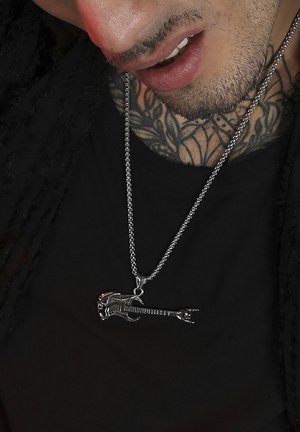 Silver necklace with a guitar pendant featuring intricate details, a textured chain, and a red accent on the guitar's body.
