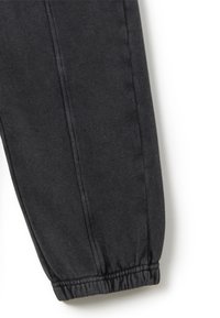 Schwarze tapered Jogginghosen aus weichem Stoff, mit einem elastischen Bündchen und sichtbaren Nähten entlang der äußeren Naht.