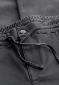 Zwarte jogger pants met een elastische tailleband, trekkoord en stiksels. Kenmerkt zich door een effen textuur en een kleine logoknop.