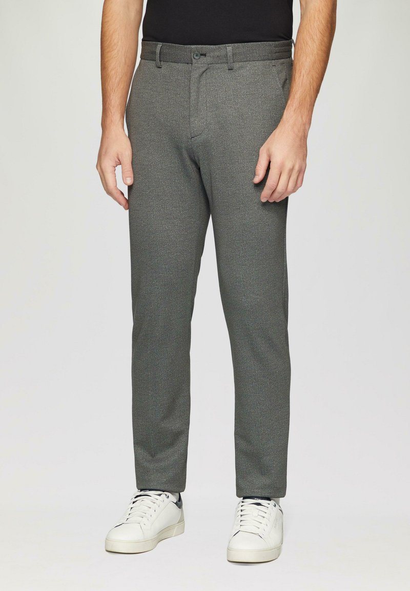 Pantalons gris texturé avec une coupe slim, dotés d'une fermeture à bouton et de poches, associés à des baskets blanches.