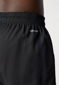 Zwarte sportshorts met een elastische tailleband, vervaardigd van een textuurstof en met het "AEROREADY" logo in het wit aan de zijkant.