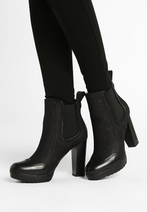 Black ankle boots with a textured fabric upper, elastic side panels, and a chunky heel. Features a smooth, rounded toe and rubber sole.