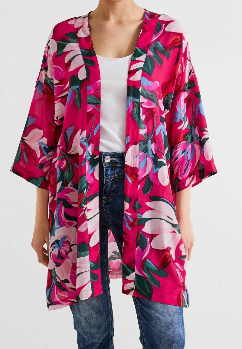 Kwiatowy kimono uszyte z lekkiego materiału; charakteryzuje się żywym różowym tłem z dużymi białymi i zielonymi wzorami kwiatowymi; luźny krój, otwarty przód.