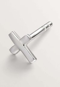 Abrebotellas en forma de cruz de plata con una superficie lisa y reflectante y un mango cilíndrico, diseñado para un agarre ergonómico.
