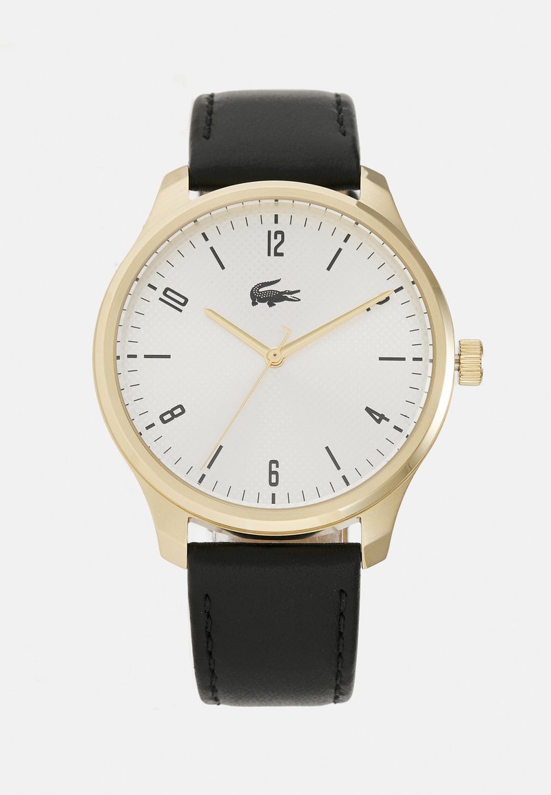 Reloj dorado con una esfera texturada blanca, marcadores de hora negros y correa de cuero negra. Presenta un logotipo a las 3 en punto y una corona.