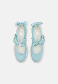 Lyseblå Mary Jane-sko med glatt overflate, hvit såle og dekorative sløyfer på reimene; enkel design med avrundet tå.