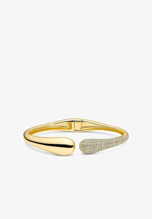 Bracelet ouvert doré avec une extrémité arrondie lisse et une extrémité effilée ornée de petits cristaux transparents. Design épuré et minimaliste.