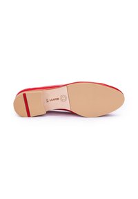 Chaussure en cuir rouge avec une finition lisse, présentant un bout arrondi et une semelle en caoutchouc beige, basse, avec texture et détails de marque.