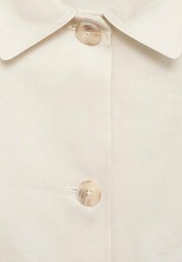 Crème shirt met kraag en een gladde textuur, voorzien van een enkele ronde knop met een gemarmerde afwerking aan de voorkant.