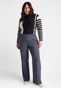 Marinblå och vit randig långärmad stickad topp i kombination med grå vida byxor med platt fram och guldtonade knappar.