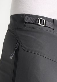 Grijze softshellshorts met een verstelbare riem, voorzien van een zijritszak en hoekige naaddetails voor een functioneel ontwerp.