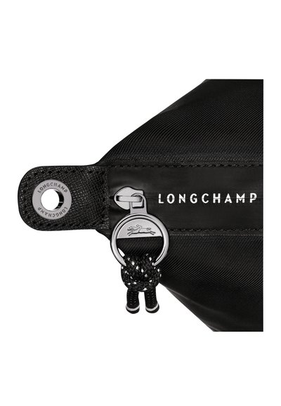 Schwarze Nylon-Tasche mit einem silbernen Reißverschluss, Longchamp-Logo und einem auffälligen geflochtenen Ziehband. Glatte Textur mit minimalistischem Design.