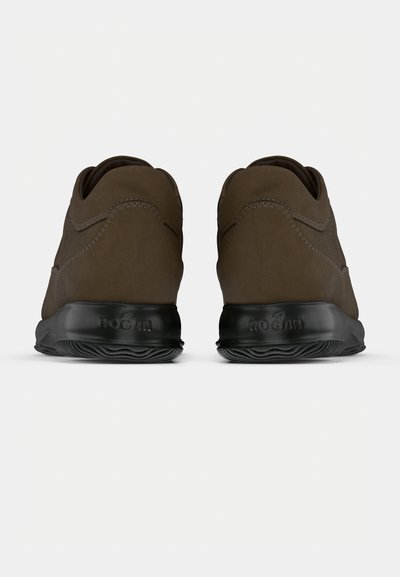 Rudos spalvos zomšiniai sportbačiai, matomi iš nugaros, su juodu guminio pado su griovelių tekstūra ir kompanijos ženklu įspaustu ant kulno.