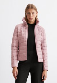 Polstret lys pink jakke med høj krave, der har horisontale quiltede sektioner, en frontlynlås og sidelommer, båret over en sort top.