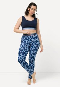 Marinblå croppad top med flerfärgade ränder, matchad med blå mönstrade leggings med abstrakta former i mörk- och ljusblå nyanser.