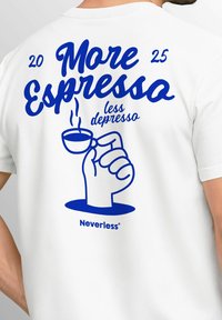 Weißes T-Shirt mit auffälligem blauen grafischen Text, der "Mehr Espresso, weniger Depresso" liest, mit einer Kaffeetasse, die von einer Faust gehalten wird.
