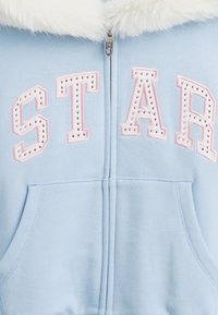 Felpa con cappuccio azzurro chiaro con zip, colletto in pelliccia sintetica, con la scritta "STAR" in rosa con strass e tasche frontali.