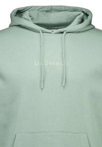 Lichtgroene hoodie gemaakt van zacht materiaal, met een voorzak, verstelbare trekkoorden en een logo-print op de borst.