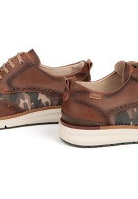 Chaussures en cuir marron avec un panneau en maille camouflage, des détails perforés et une semelle intermédiaire blanche avec des accents rouges. Design à bout arrondi.