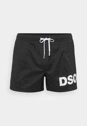 Schwarze Badeshorts mit weißem Kordelzug und großem, teilweise weißem "DSQ"-Logo am rechten Bein, mit subtilem wiederholtem Schriftzug "DSQUARED2".