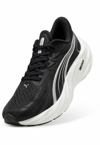Baskets de course noires avec un upper texturé, présentant un design rayé blanc et argent, une semelle rembourrée et un système de laçage.