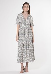 Maxi-Kleid aus leichtem Stoff mit grünen und weißen Blattmustern, tiefem V-Ausschnitt, kurzen Ärmeln und gerafftem Bund für eine fließende Silhouette.