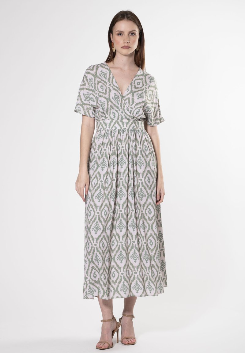 Maxi-Kleid aus leichtem Stoff mit grünen und weißen Blattmustern, tiefem V-Ausschnitt, kurzen Ärmeln und gerafftem Bund für eine fließende Silhouette.