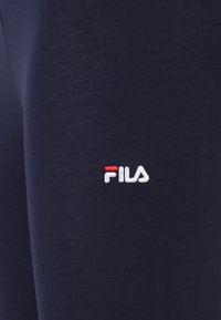 Donkerblauwe sportbroeken gemaakt van zacht materiaal, met een kleine geborduurde FILA-logo in het wit en rood op het dijgebied.