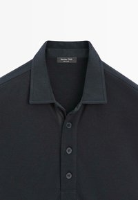 Czarna koszulka polo z krótkim rękawem, z trzema guzikami i sztywnym kołnierzykiem, z metką "Massimo Dutti" wewnątrz dekoltu.
