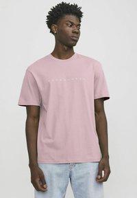 Hellrosa Baumwoll-T-Shirt mit kurzen Ärmeln. Verfügt über einen runden Halsausschnitt und ein weißes "JACK & JONES"-Logo über der Brust. Weicher Stoff.