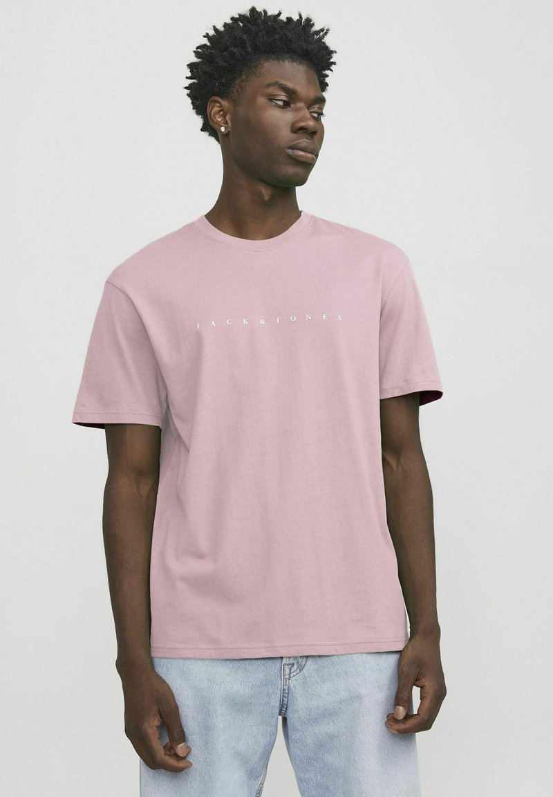 Hellrosa Baumwoll-T-Shirt mit kurzen Ärmeln. Verfügt über einen runden Halsausschnitt und ein weißes "JACK & JONES"-Logo über der Brust. Weicher Stoff.