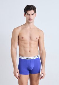 Männer Boxershorts in Blau mit einem weißen Bund, auf dem das Nike-Logo zu sehen ist. Glattes Material, taillierte Passform, mittlere Länge, ohne Muster oder Akzente.