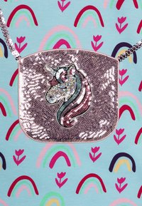 Lesklá stříbrná kabelka ve tvaru jednorožce s flitry. Obsahuje řetízek na nošení a plochý design. Pozadí má barevné vzory duhy a květin.