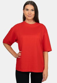T-shirt in cotone rosso con vestibilità rilassata, maniche corte e scollo rotondo. Tessuto liscio e colore uniforme senza motivi o decorazioni.