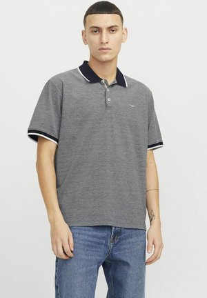 Grå pikétröja med marinblå krage, vita detaljer och tre knappar. Korta ärmar och mjuk textur. Bärs med blå denimjeans.