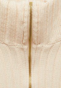 Knit sweater in soft pink with a central gold zipper. Features ribbed texture and a high collar, emphasizing a cozy design.