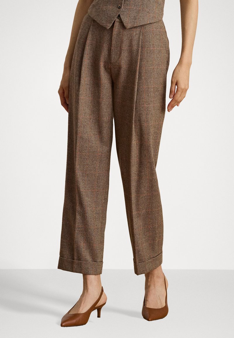 Braune, gemusterte Hose mit lockerer Passform, mit Falten an der Vorderseite und umgeschlagenen Säumen. Kombiniert mit braunen Slingback-Absätzen.