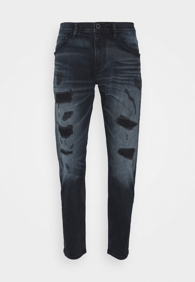 Tmavě modré džínové kalhoty s poškozením, obsahující několik roztržených částí a slim fit střih. Standardní pětikapsový styl.