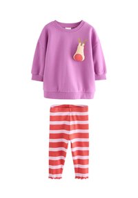 Paarse trui met een rendierapplicatie op de borst, gecombineerd met rood-wit gestreepte legging met een geschulpte zoom bij de enkels.