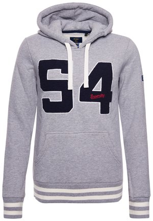 Jasnoszara bluza z kapturem z białymi sznurkami, duża granatowa "94" z przodu, mały czerwony napis "Superdry" oraz paski na ściągaczach i dole.