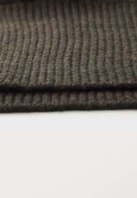 Mørk stripet stoff som viser fine, teksturerte detaljer; har en myk ullblanding med en subtil glans og folder som skaper dybde.