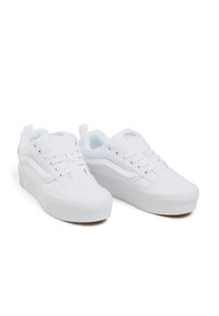 White sneakers with a canvas upper, lace-up design, platform sole, and logo on the tongue. Smooth texture and minimalistic style.