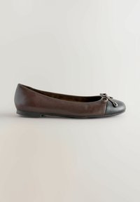 Ballerines en cuir marron avec un bout noir, dotées d'un nœud décoratif et d'une semelle à profil bas pour un design épuré.