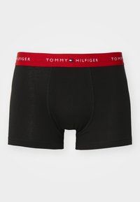 Boxer shorts noirs en coton avec une ceinture élastique rouge portant "TOMMY HILFIGER" en lettres blanches.