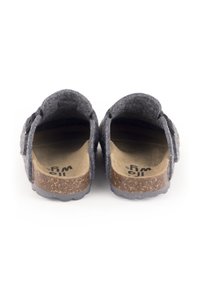 Chaussures slip-on grises en feutre avec une semelle en liège, présentant un design arrondi et un détail de sangle à l'avant. L'intérieur a une finition lisse.