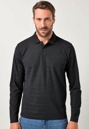 Camisa polo negra de manga larga con un patrón texturizado, tapeta de tres botones y cuello, acompañada de unos vaqueros de mezclilla azules.