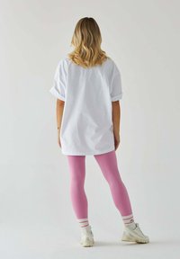 Bia�ła, oversize'owa koszulka i różowe legginsy, do tego paskowane białe i czerwone skarpetki. Strój charakteryzuje się luźnym krojem i casualowym wyglądem.